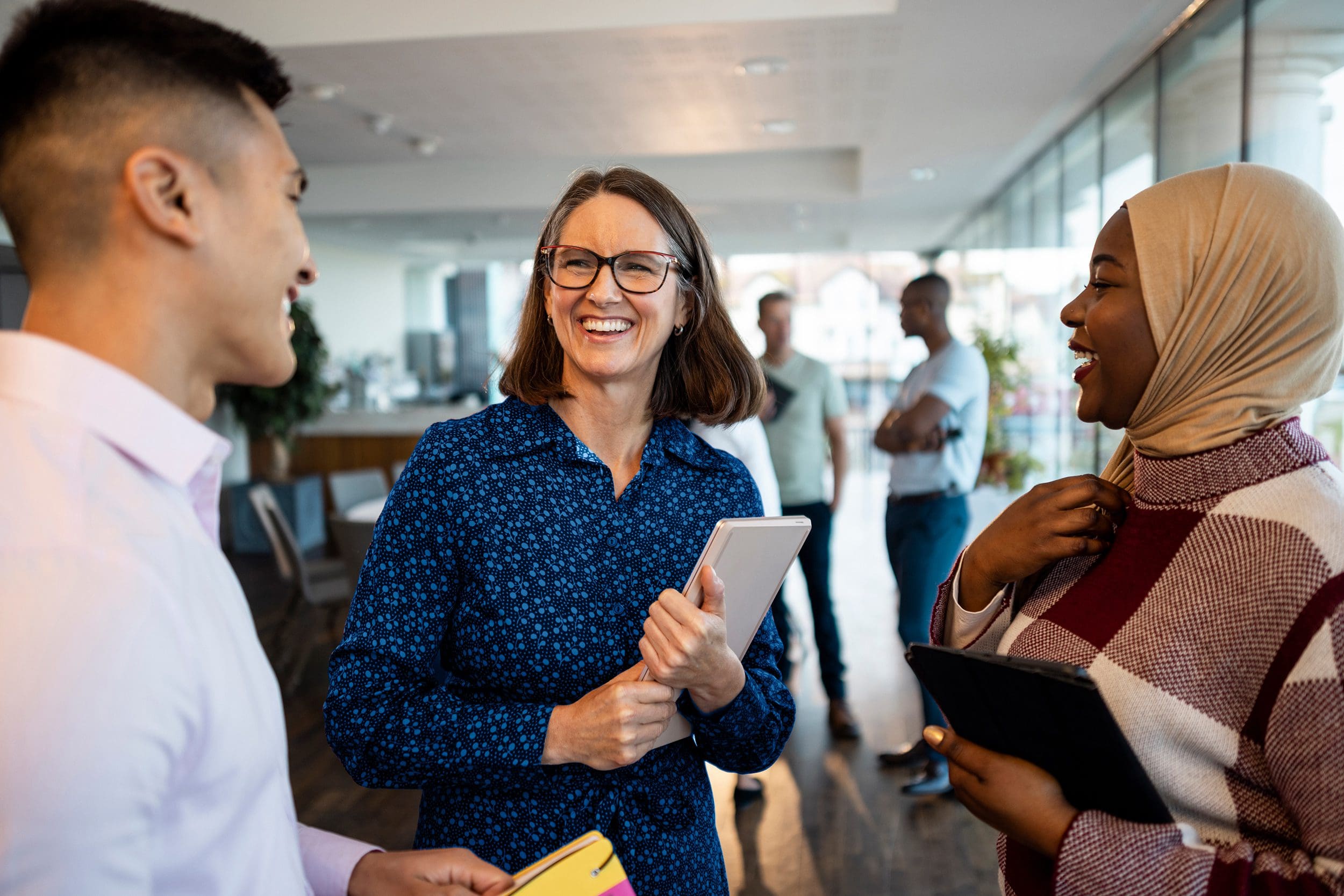 Three smiling colleagues chatting in a meeting room